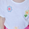 White shirt with colorful flower designs on a plain background