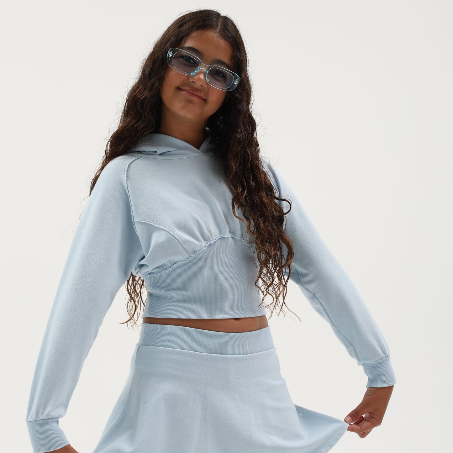 Girl wearing a light blue dolman sleeve hoodie with matching skirt