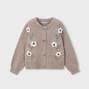A taupe knit cardigan sweater with embroidered white flowers and green leaves on the front, featuring a button-up closure, shown against a light gray background.