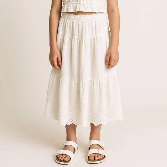 tween wearing a white tiered skirt on a plain background