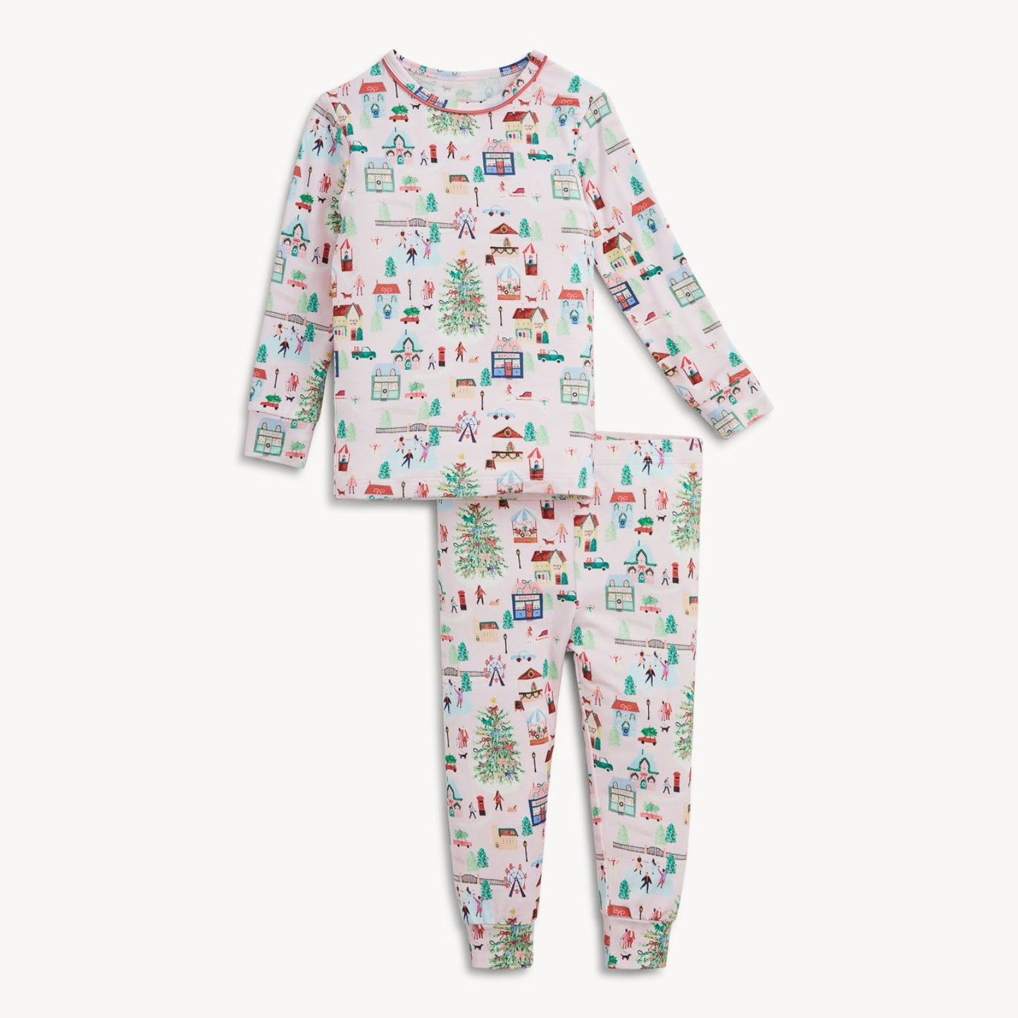A two-piece children's pajama set featuring a long-sleeve top and matching pants with an all-over Christmas village print on a white background.