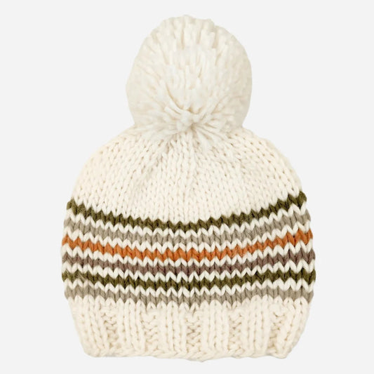 An off-white chunky knit pom-pom beanie with horizontal zigzag stripes in olive green, brown, and orange, shown against a light gray background.