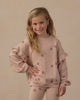 Child playing indoors wearing the Clay Stars Ruffle Sweatshirt