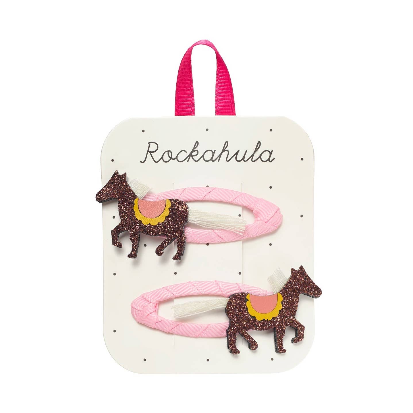 Two pink hair clips with glittery brown carousel horse charms, displayed on a white card with a pink ribbon loop and the brand name 'Rockahula'.