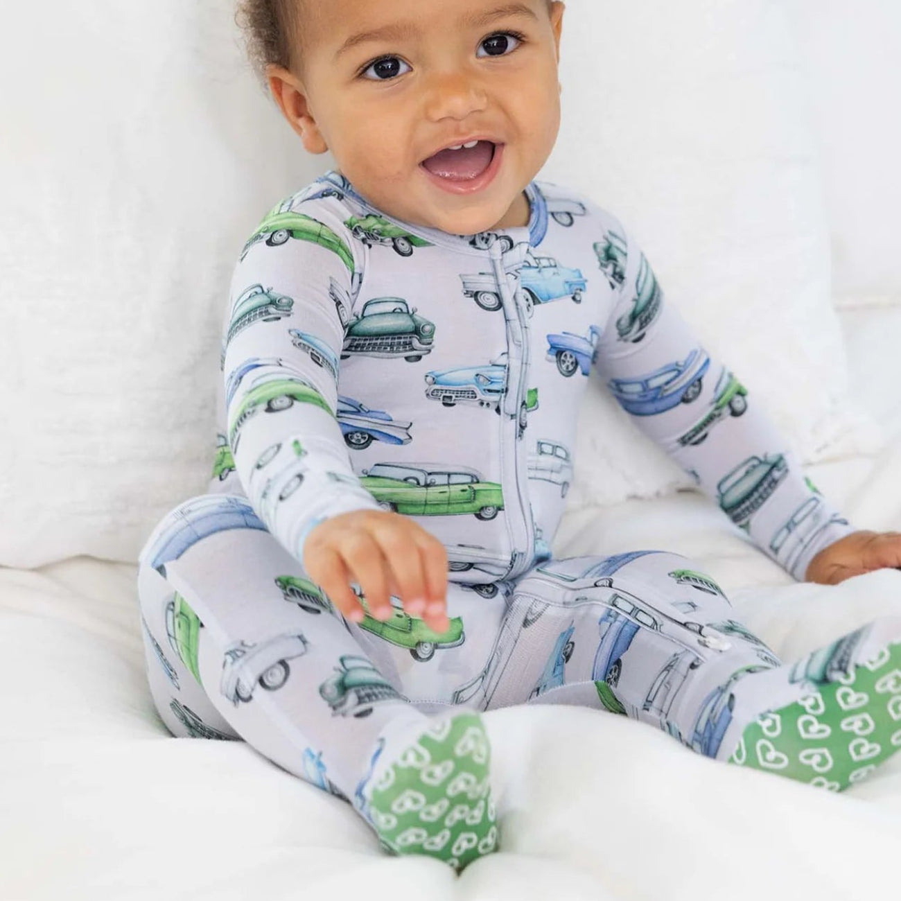 Baby wearing pajamas with car patterns on a white blanket