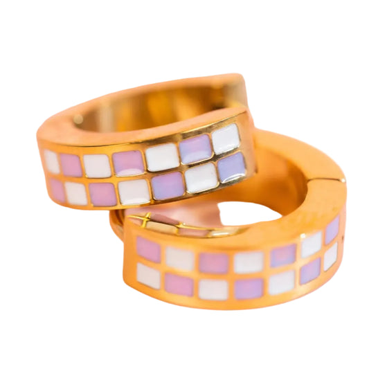 Gold hoop earrings with colorful square pattern on a pink background