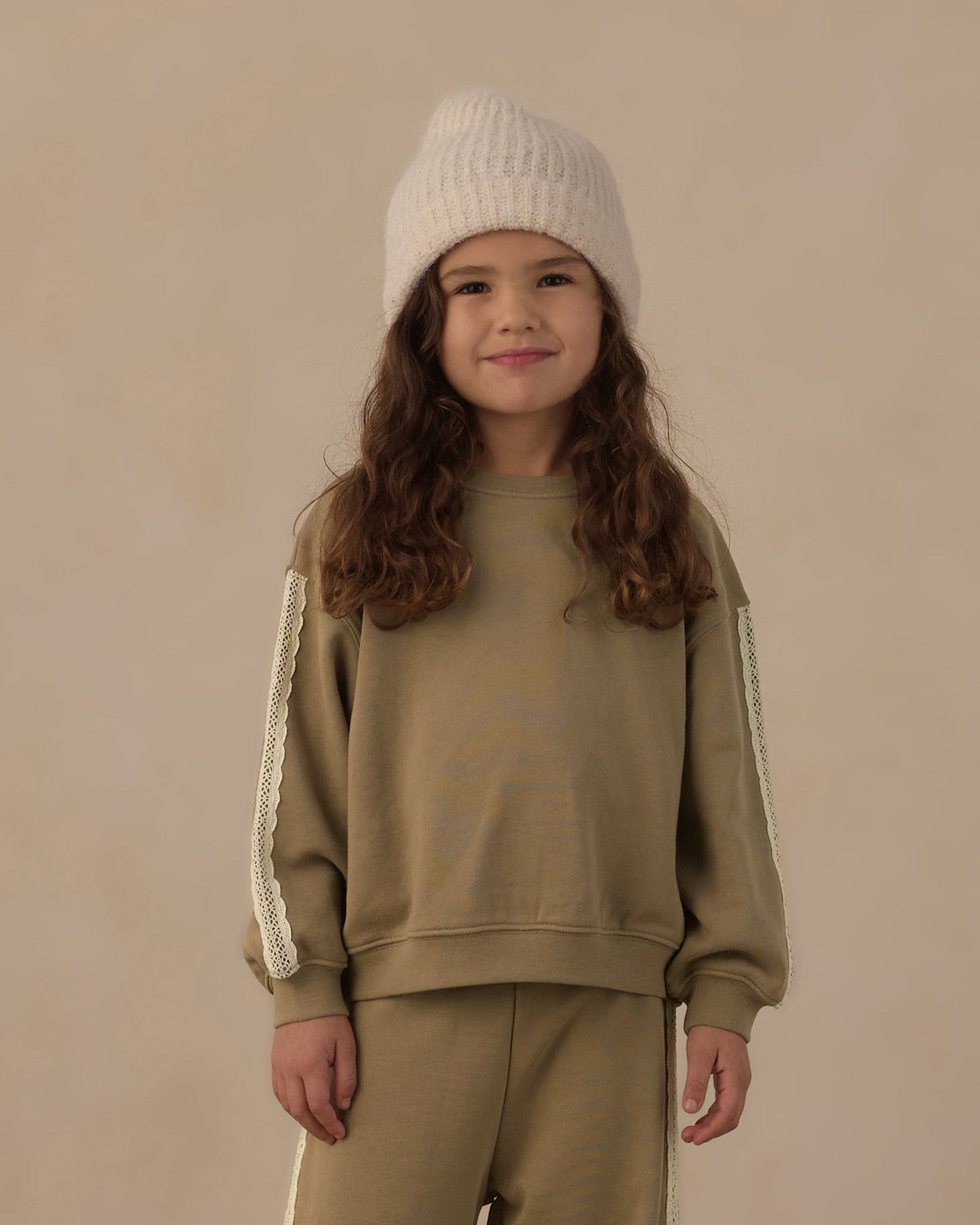 Child wearing the olive oversized sweatshirt with lace trim