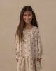 Girl standing in the Pink Daisies Swing Dress showing the gathered lower tier