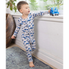 Child wearing a car-patterned onesie holding a toy car indoors.