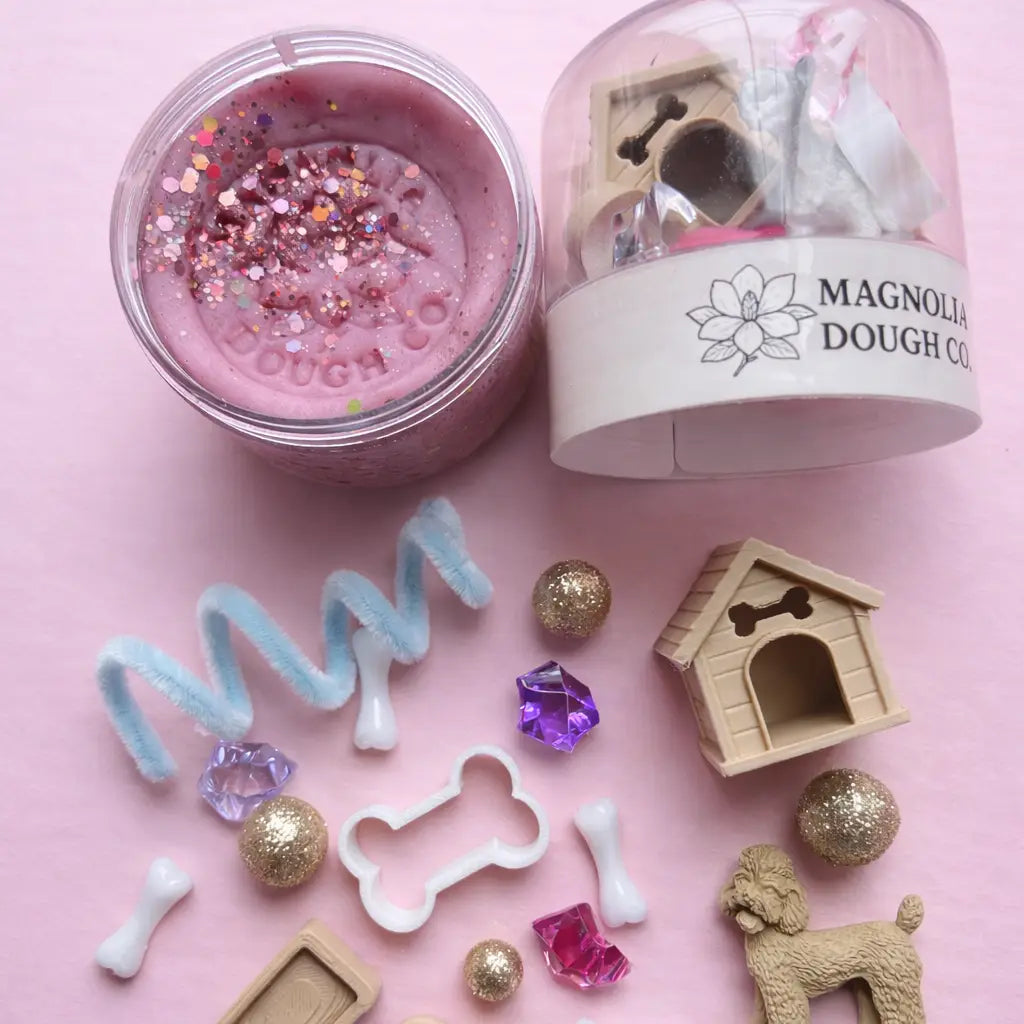 Jar of play dough with a mini puppy toy figure, featuring Magnolia Dough Co. branding.