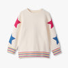 Beige sweater with colorful star patterns on sleeves and hem against a white background
