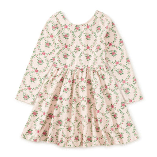 A long-sleeve baby dress with a tiered skirt, featuring an all-over floral print in pink and green on a warm cream background, shown flat on a white background.