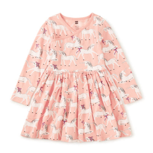 A pink long-sleeve baby dress with an all-over unicorn print, featuring a gathered waist and V-neckline, shown flat on a white background.